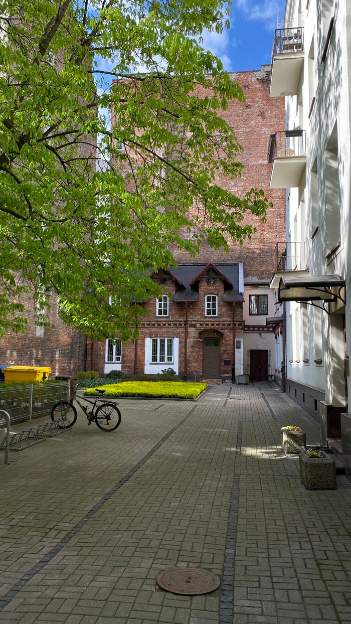 Quaint courtyard in Warsaw with bicycles and brick buildings under a clear sky.